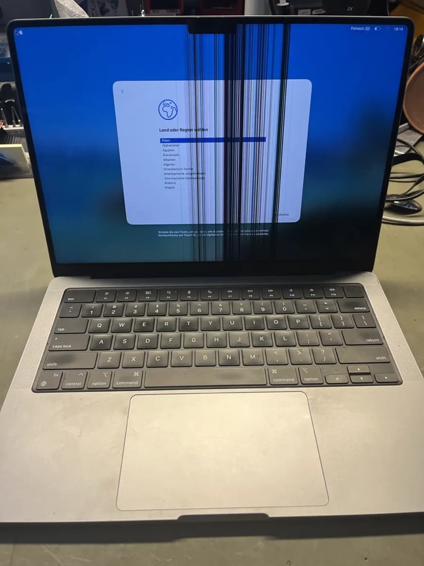 MacBook z uszkodzoną matrycą — pionowe pasy i zniekształcony obraz na ekranie podczas konfiguracji systemu